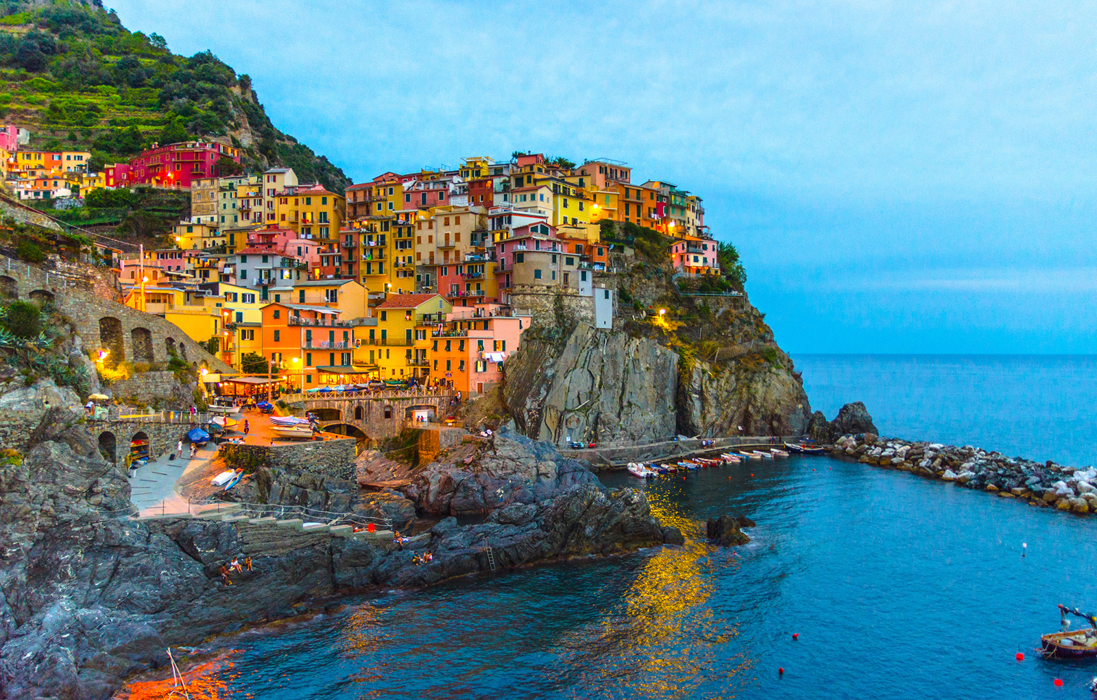 Manarola traditional typical Italian village in National park Cinque Terre with colorful multicolored buildings houses on rock cliff and marine harbor, night evening view, La Spezia, Liguria, Italy