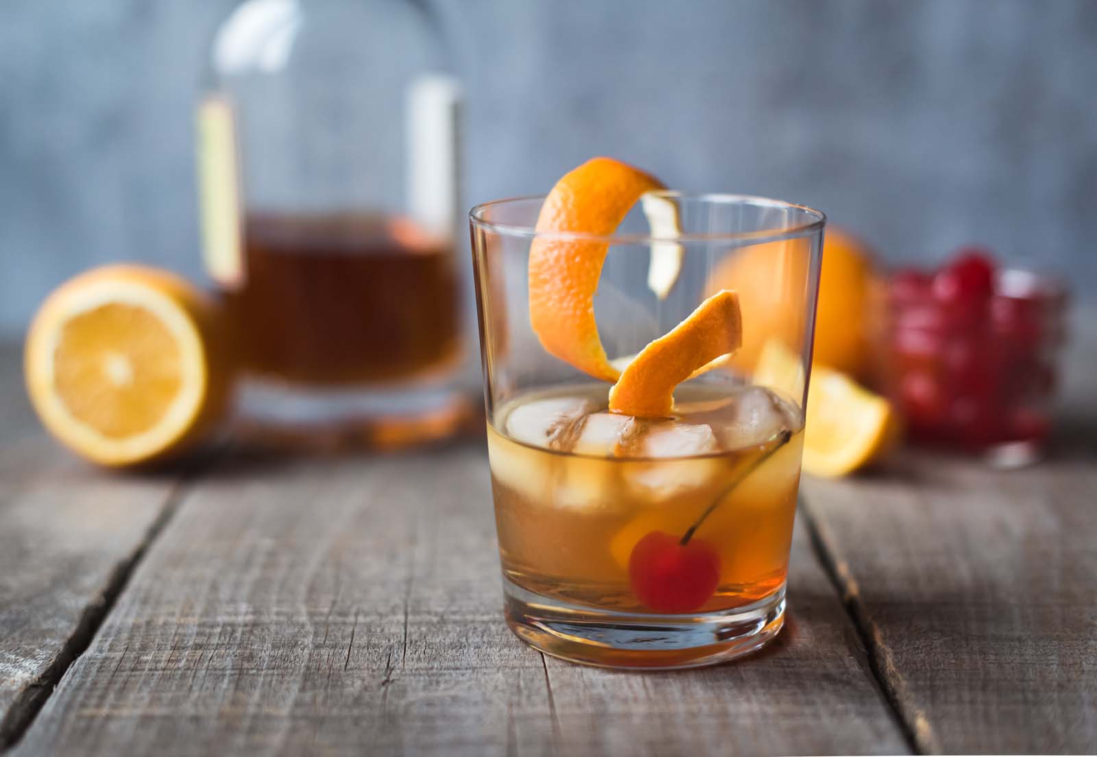 Close up of old fashioned cocktail with ingredients on wooden table.