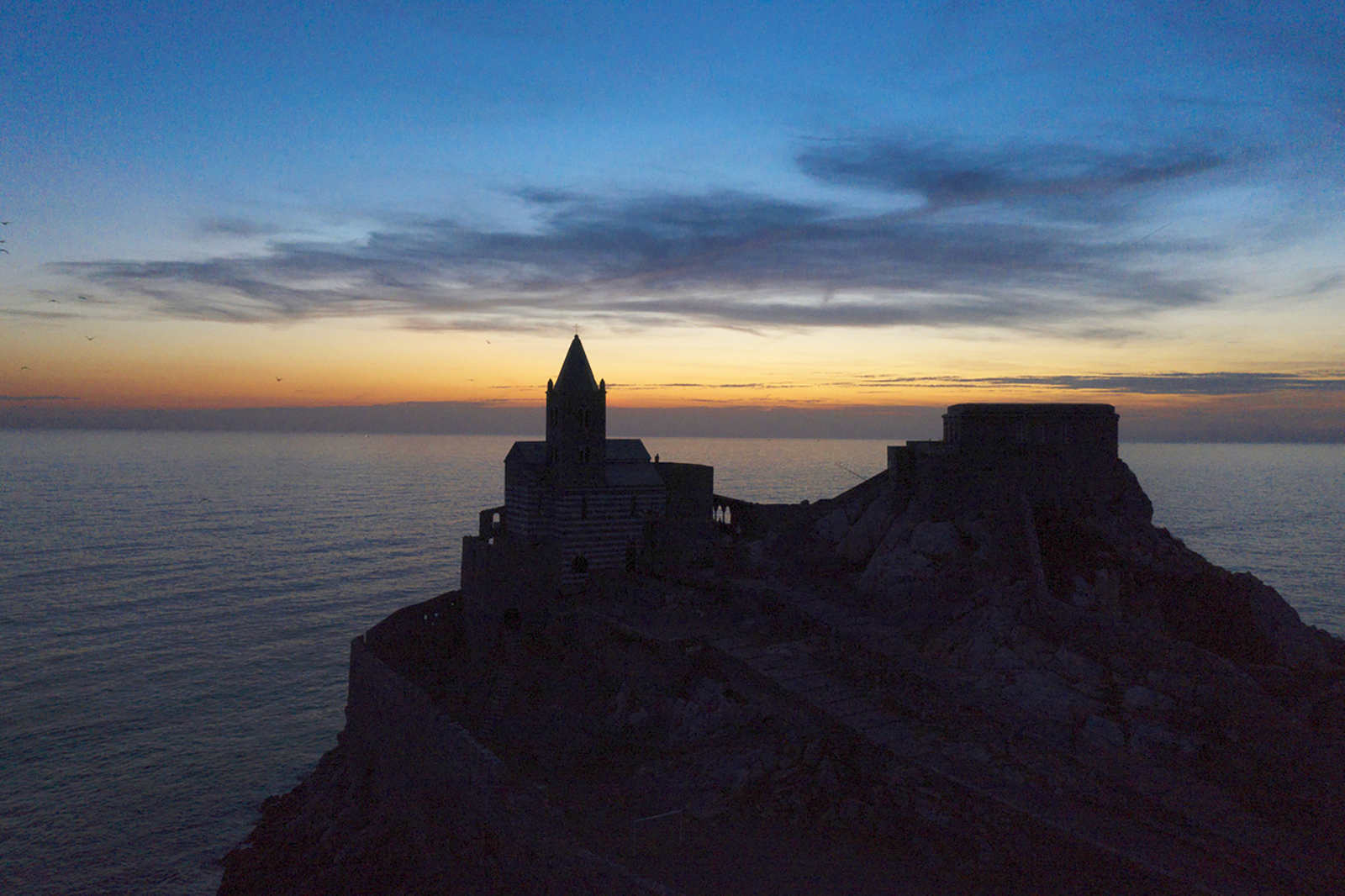 aerial photo with silhouettes of the church of San Pietro in Portovenere with sunset in the background