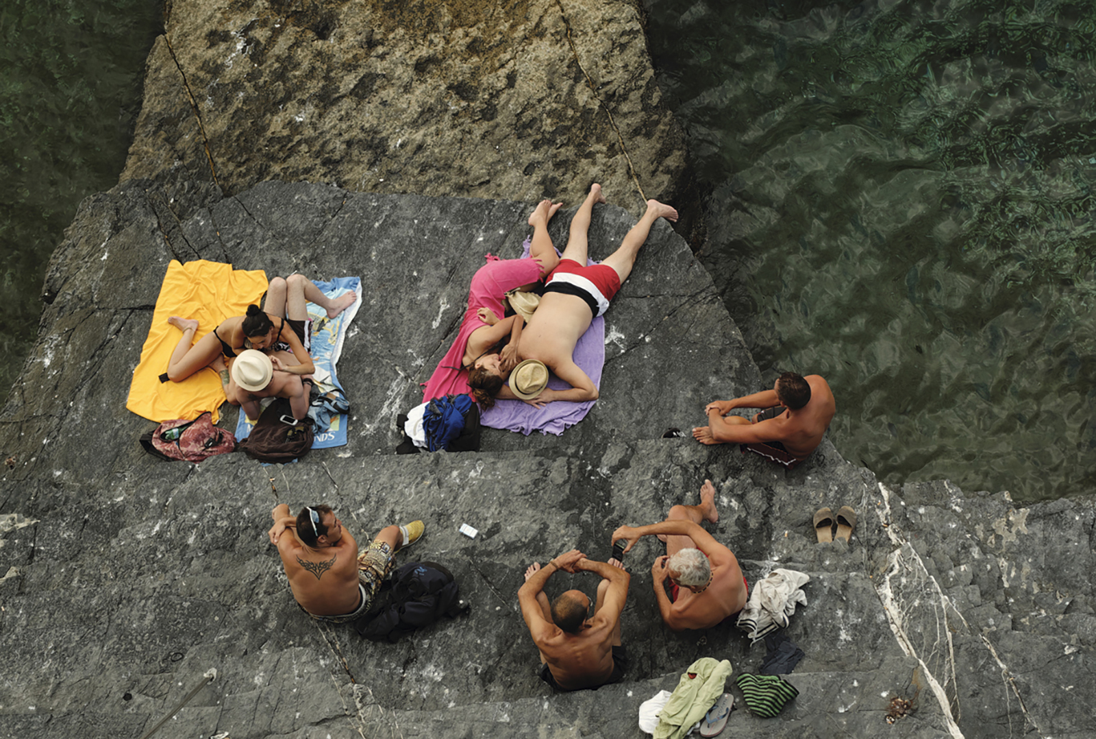 Sunbathers like dashes of colours in Portovenere, Italy