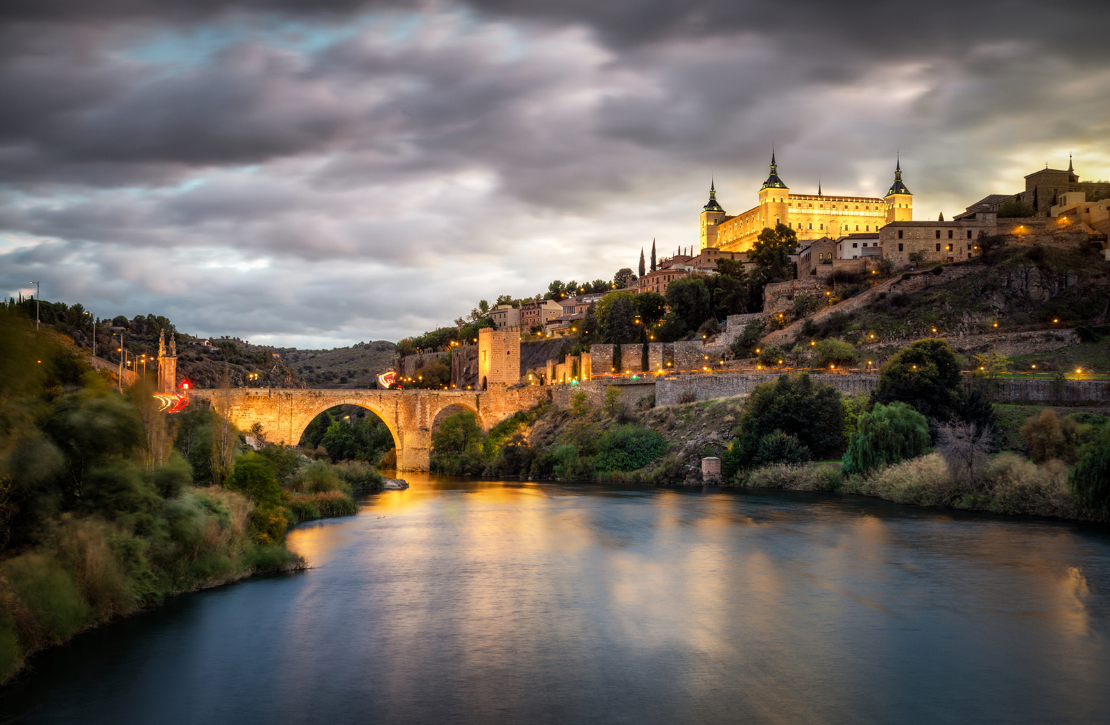 alcazar and alcantara bridge in Toledo at sunset reflected in Tajo river
