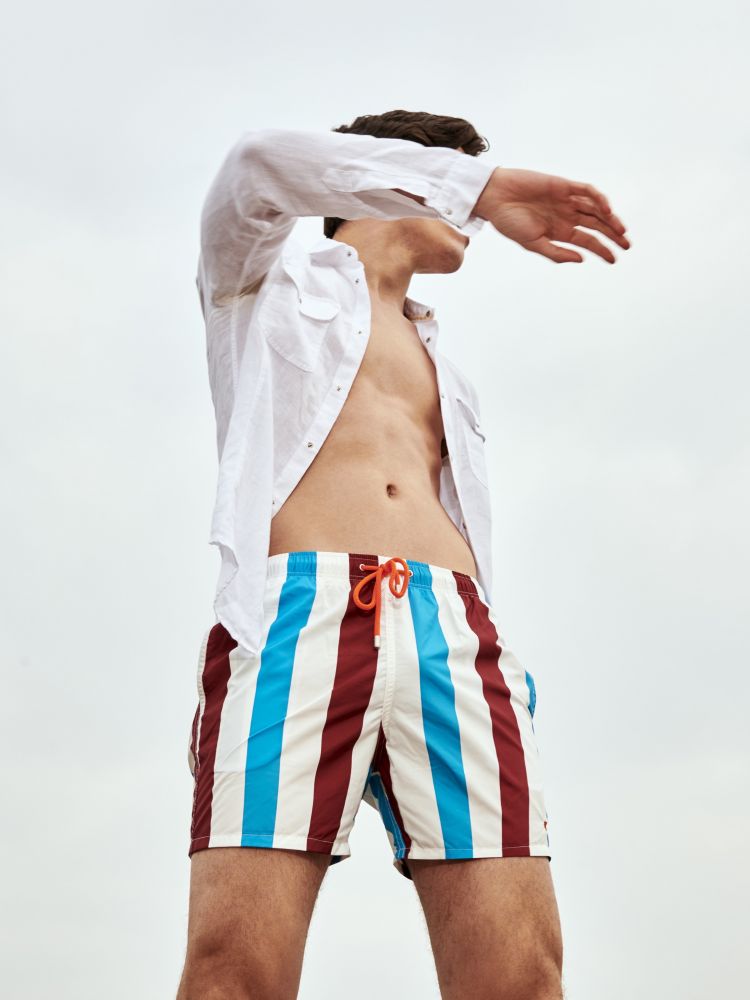 Gallo boxer mare uomo in poliestere bianco azzurro e bordeaux a righe. Un costume da uomo modello boxer realizzato in Italia con fibre sintetiche. L'elastico in vita garantisce il massimo comfort mentre la fantasia a righe mantiene una connessione con la tradizione Gallo, sinonimo di qualità ed eccellenza italiana dal 1927.