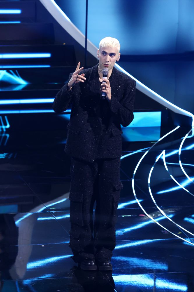 Per la prima volta al Festival di Sanremo Mr. Rain indossa un completo sartoriale nero incrostato di Swarovski scintillante di GCDS e gioielli Damiani. Porta sul palco la sua canzone “Supereroi” intonata insieme ad un coro di bambini seduti sulla scalinata del palco dell’Ariston.