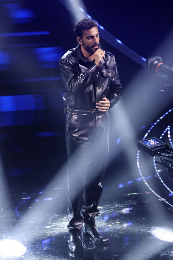 Si presenta con un look in total leather con la canzone intitolata “Due vite”. Marco Mengoni dopo la vittoria con la canzone “L’essenziale”, ritorna al Festival di Sanremo 2023 con un testo emotivo che riassume il significato nel percorso e le esperienze della vita. Un completo Versace in pelle nera elegante con bottoni in oro che riportano il simbolo della Medusa scelto dallo stylist Lorenzo Posocco.