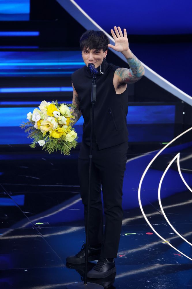 Ultimo indossa un look total black di Emporio Armani strutturato con un top smanicato con collo ad imbuto, pantaloni slim fit e sneakers in pelle nera. Per il Festival di Sanremo 2023 porta sul palco la sua canzone “Alba” con un attitudine sportiva, giovanile e contemporanea.
