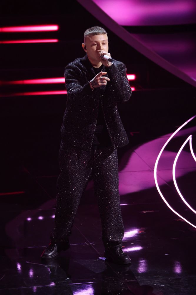 Lazza approda per la prima volta al Festival di Sanremo 2023 e porta sul palco la canzone “Cenere”. Sul palco dell’Ariston indossa un completo total black scintillante di Missoni scelto dallo stylist Simone Furlan. Una canzone fresca supportata con un look contemporaneo e cool.