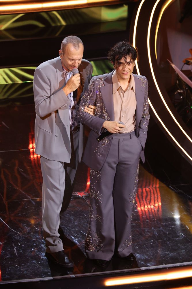 Tananai continua a sfoggiare look retró indossando un total look Gucci grigio tempestato di strass e swarovski. Per la quarta serata di Festival, duetta con Biagio Antonacci che indossa un completo Giorgio Armani abbinato per cromia al cantante in gara. Accurati e l’effetto della performance è un po’ un’esibizione ‘padre figlio’.