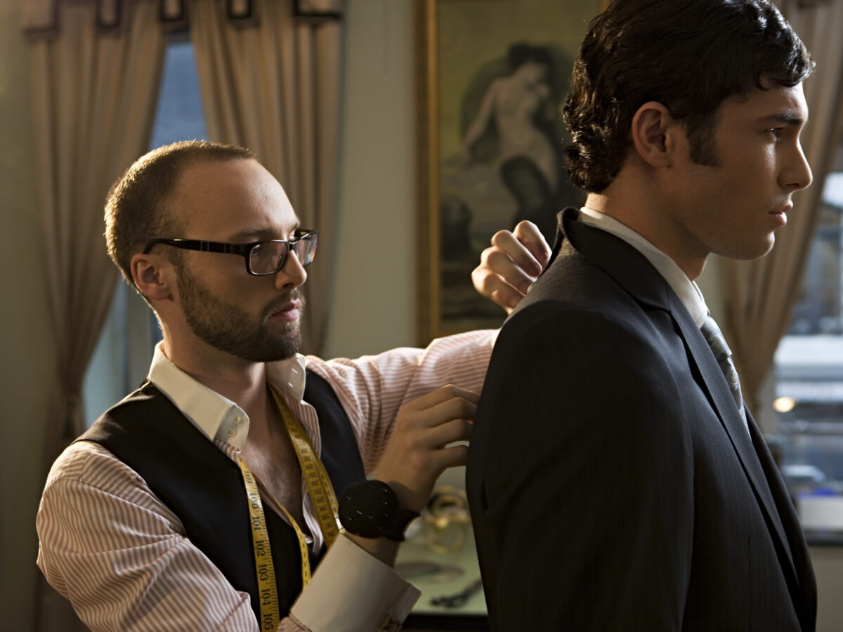Tailor adjusting suit on man, close-up