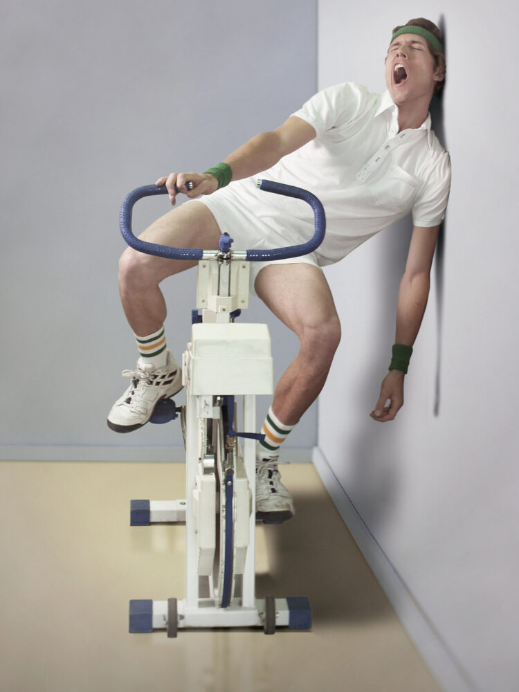 Man yawning while sitting on exercise bicycle