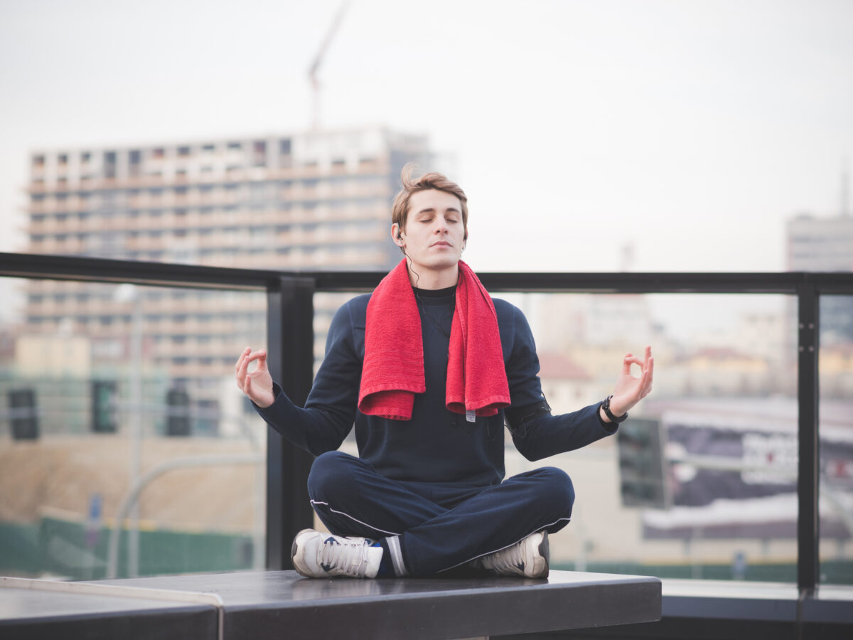 Young man practicing lotus yoga position on city rooftop