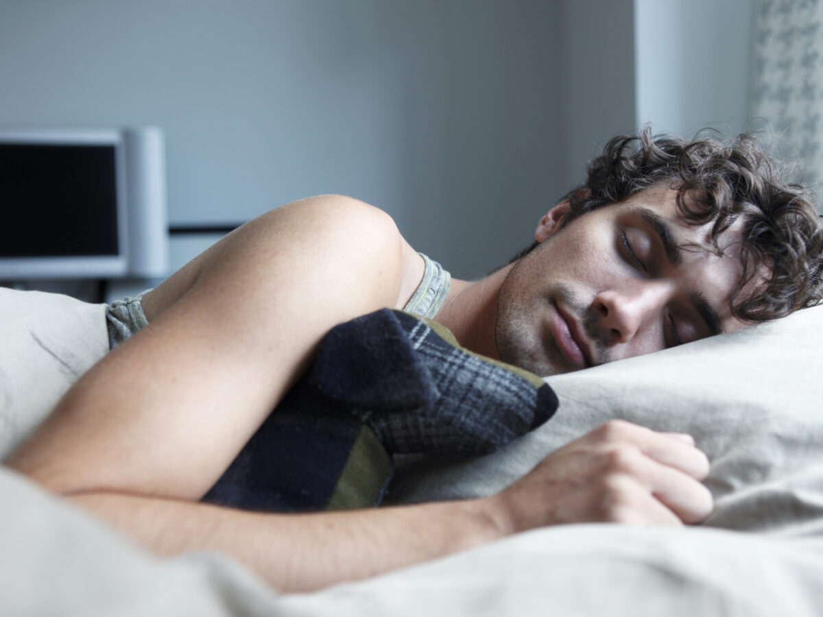 Man sleeping in bed with stuffed animal