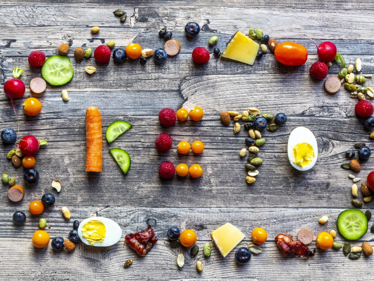 Keto shaped from fruits and vegetables, framed by divers food
