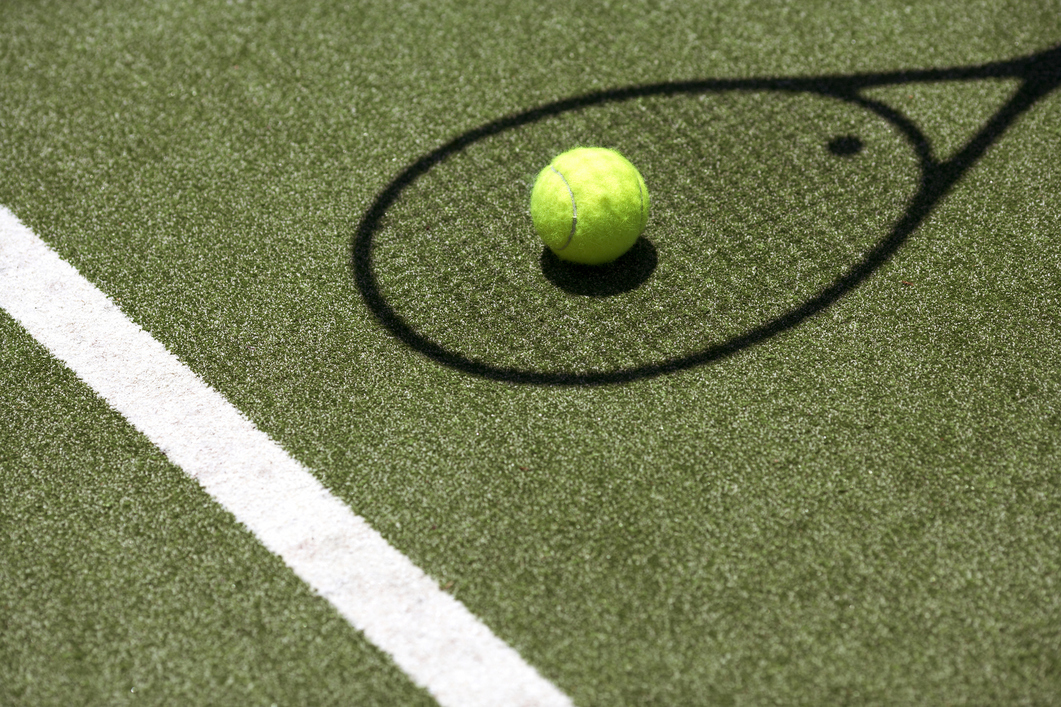 Tennis ball with racket shadow on court